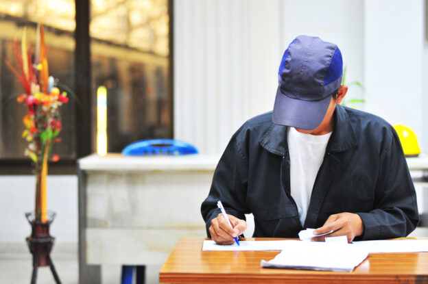 man wearing a blue ball cap working on his freight broker license paperwork