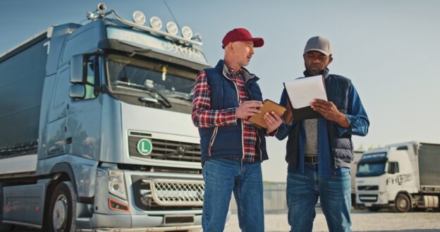 Two employees standing in front of a truck.