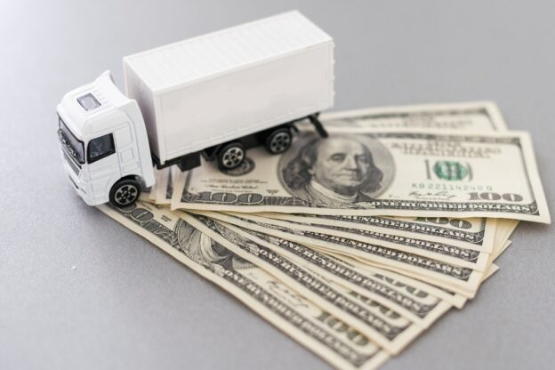 White toy truck lie on dollars.