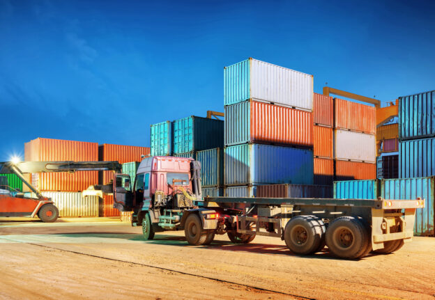 Container terminal at night, stopped working forklifts and trucks.