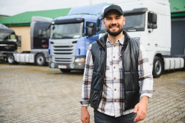 An owner operator standing infront of trucks.